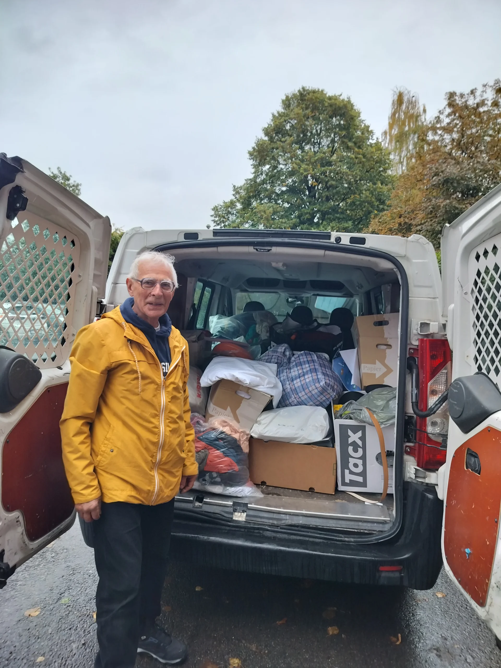 🕊️ Say Hi For Peace 2023 4 un homme agé pose devant le derrière d'une camionnette remplie de dons pour l'ASBL BelRefugees