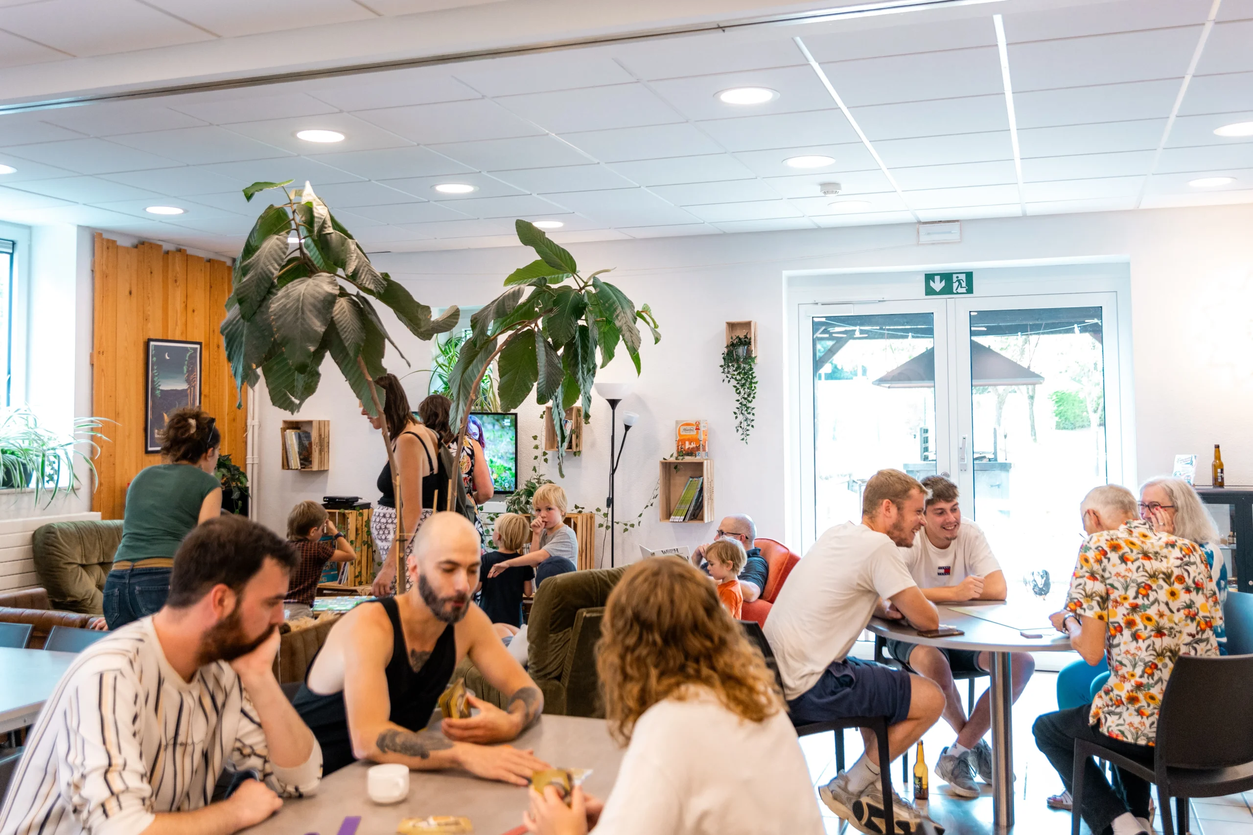 🌈Tournoi Skyjo 3 Grande salle avec plusieurs personnes de tout âge, tout sexe jouant à des jeunes de société autour de tables