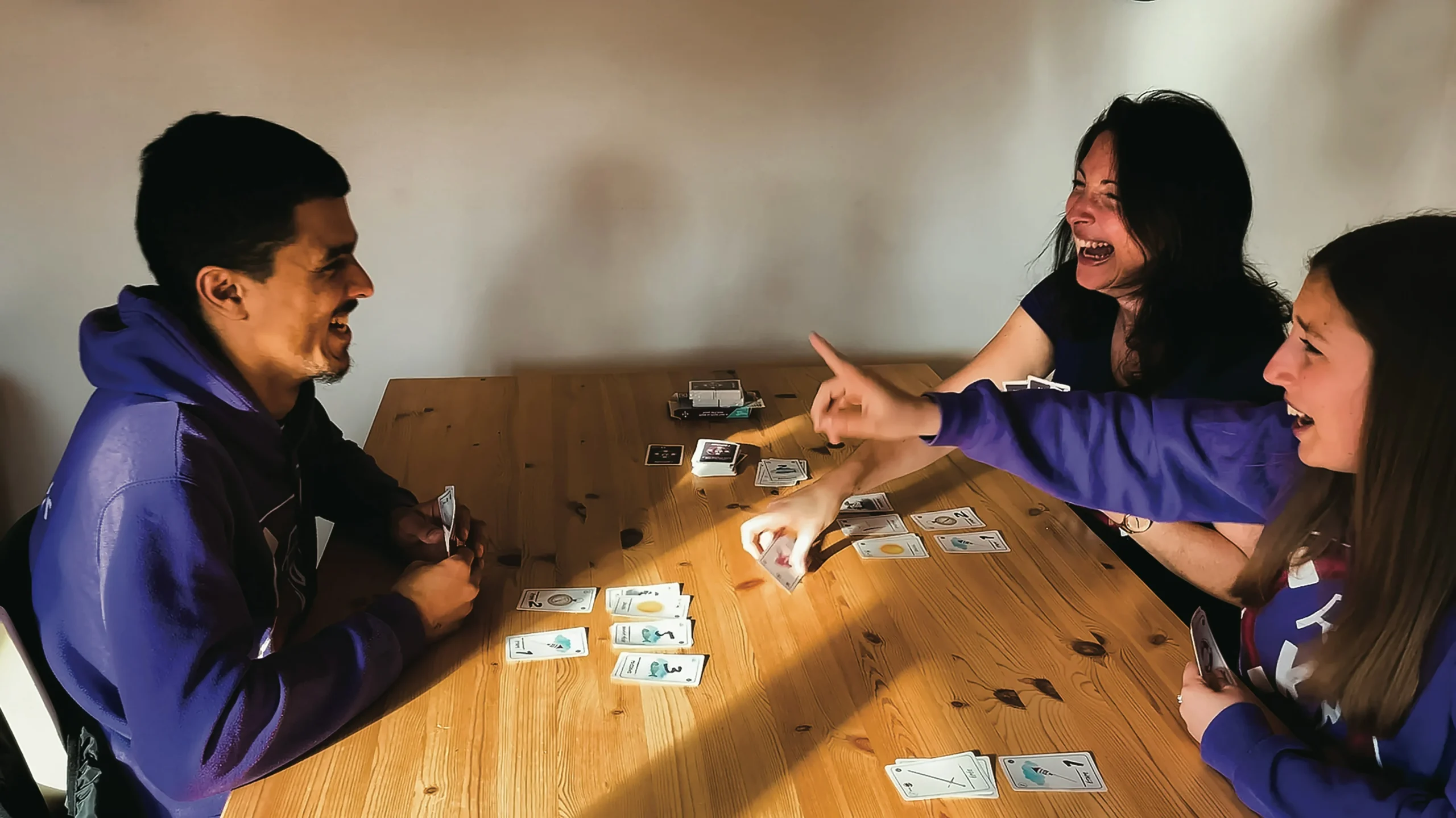 🃏 Les jeux de société : bien plus qu’un divertissement 2 famille qui jouent à un jeux de carte en rigolant